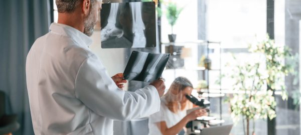 Bones pictures on the x-ray. Two clinic workers are indoors together. Senior man with young woman