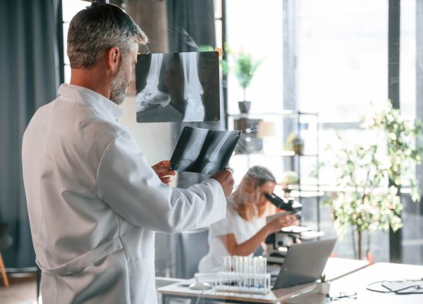 Bones pictures on the x-ray. Two clinic workers are indoors together. Senior man with young woman