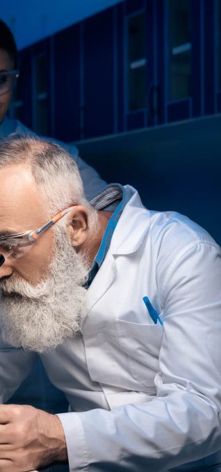 concentrated scientist using microscope while colleague holding